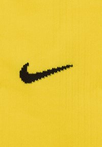 Gele gebreide stof met een zwart Nike swoosh-logo, met een gladde textuur en opvallende contrasterende kleuren.