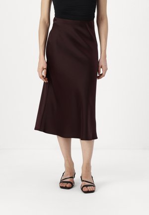 Bordeauxfarvet satin midi nederdel med en glat tekstur, der har et flydende design og subtil drapering, kombineret med sorte sandaler med stropper.