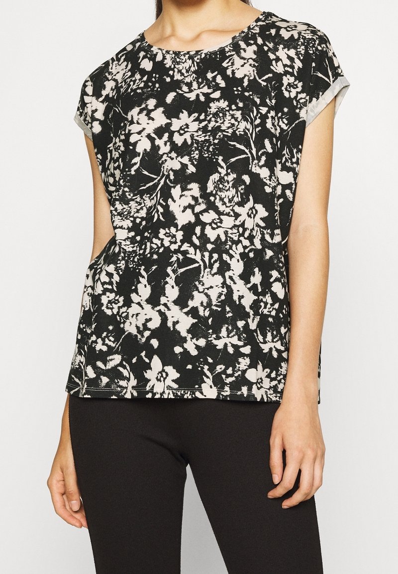 Černobílé květinové tričko s krátkým rukávem, kulatým výstřihem a volným střihem, vyrobené z měkké, texturované látky.