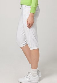 Vita capribyxor i mjukt tyg, med elastisk midja och rynkade manschetter. Bärs med vita sneakers och texturerade strumpor.