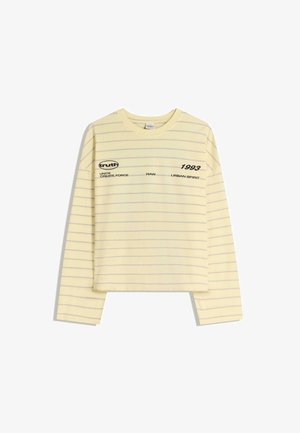 Keltainen, pitkähihaisen T-paita, jossa on harmaat raidat. Rinnassa mustalla painettua tekstiä, kuten "truth" ja "1993". Lyhyt, vartalonmyötäinen malli.