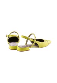 Żółte lakierowane sandały typu slingback z ostrym noskiem, ozdobione srebrnymi ćwiekami, niskim blokowym obcasem oraz regulowanym paskiem wokół kostki.