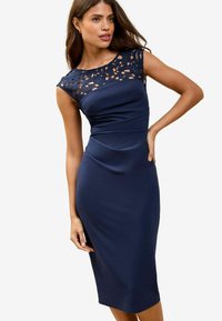 Navyblaues Kleid mit figurnaher Silhouette, das ein Spitzen-Schulterdesign aufweist und aus glattem, geschmeidigem Stoff bis zur Mitte der Wade reicht.