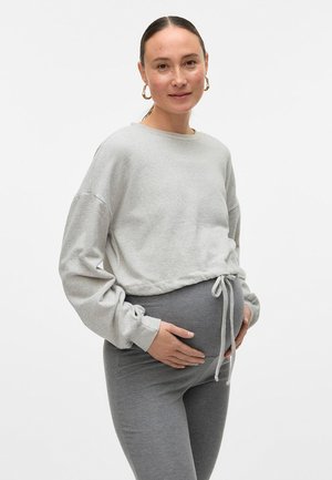 Sweatshirt gris court avec de longues manches et un ourlet à cordon, associé à des leggings gris, tous deux en tissu doux, portés par une personne tenant son ventre.