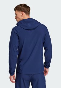 Marineblauwe hoodie met elastische manchetten en een relaxed fit. Gemaakt van lichtgewicht, soepel materiaal, met een eenvoudig ontwerp zonder zichtbare logo's.