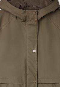 Giacca impermeabile color khaki con cappuccio foderato in pile, bottoni a pressione metallici e cuciture ben visibili. Materiale esterno liscio con finitura opaca.
