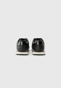 Svarte joggesko i glatt skinn med teksturerte bakdetaljer. Har en hvit såle og minimalistisk design uten synlig merke.