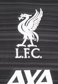 Tessuto nero con un design testurizzato presenta un logo ricamato bianco del Liverpool FC e il testo "L.F.C.", accanto a "AXA" in lettere bianche in grassetto.