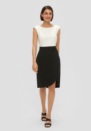Robe noire portefeuille avec un buste blanc ajusté, des manches courtes et une fente sur le côté. Texture lisse et design minimaliste souligné par une silhouette élégante.