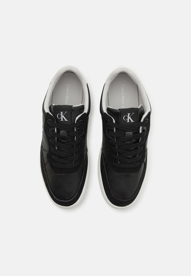 Baskets en cuir noir avec des accents en textile, bout rond, semelle blanche et design à lacets. Présente un logo sur la languette et un intérieur doux.