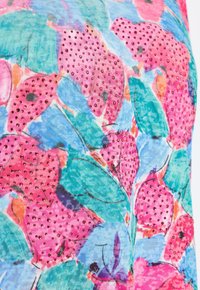 Tessuto floreale colorato con fiori rosa e foglie verdi, caratterizzato da piccoli borchie rosse. Lo sfondo presenta una texture blu chiaro.