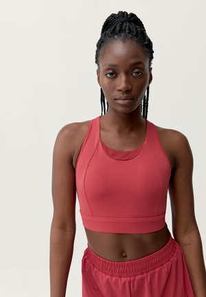 Top corto atlético rojo, diseño ajustado con un escote redondeado, combinado con pantalones cortos rojos sueltos y gatherados. Textura de tela suave y elástica.