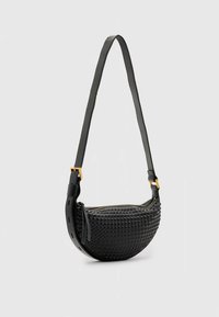 Musta, kuvioitu käsilaukku puolikuun muotoinen, jossa on vetoketjusuljin ja irrotettava hihna. Kultaiset metalliosat ja geometrinen kuvio.