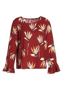 Blouse rouge à manches longues avec un motif floral abstrait crème, marine et moutarde, des poignets évasés, un col rond et une fermeture par œillet au dos.