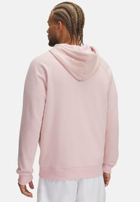 Haut à capuche rose clair avec une texture douce, comportant une capuche, des manches longues et unourlet côtelé. Aucun motif ou accent visible.