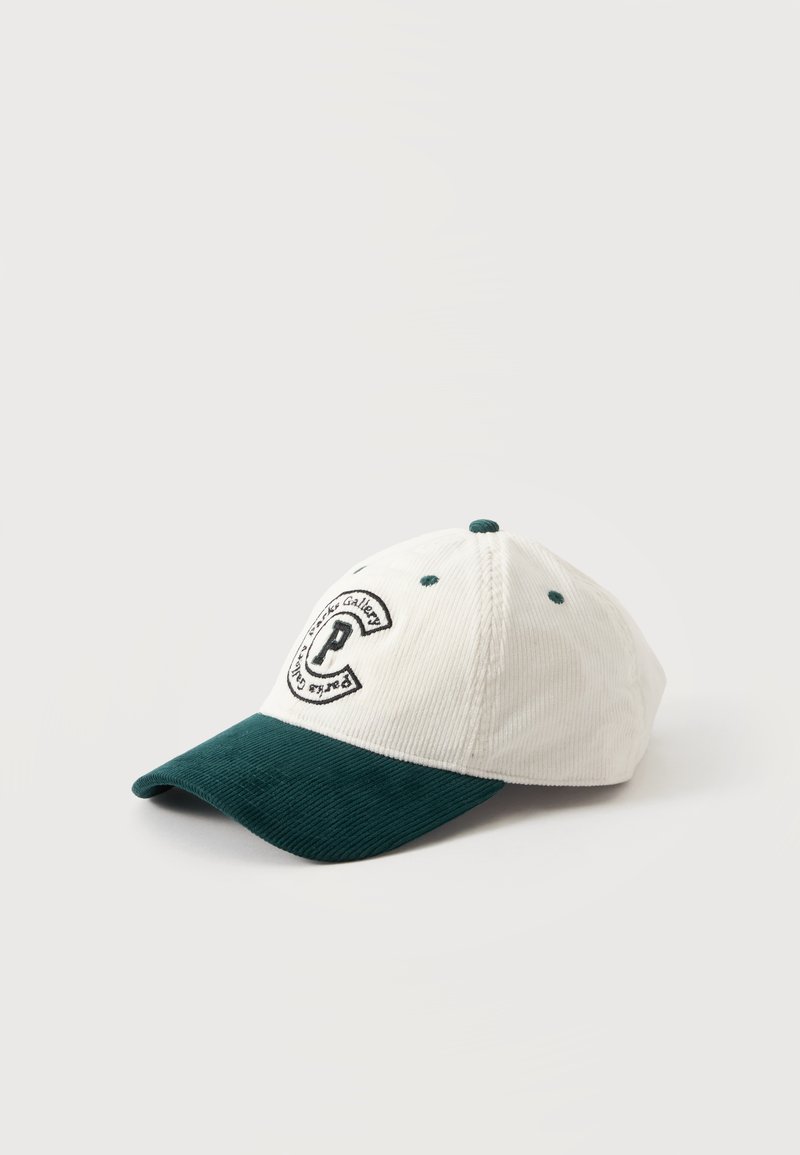 Casquette de baseball blanche et vert foncé avec un logo rond présentant la lettre P à l'avant, posée sur une surface claire et unie.