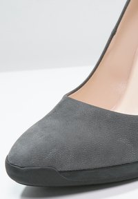 Escarpin en suède gris à bout pointu, avec une doublure intérieure lisse et une surface texturée. Semelle extérieure en caoutchouc noir pour une meilleure traction.