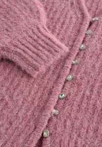 Blød lyserød fuzzy strikket cardigan med ribbede manchetter og krystalbesatte knapper, der løber ned ad forsiden.