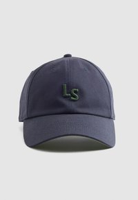 Casquette bleu marine en coton avec une visière courbée. Présente des lettres brodées vertes "LS" à l'avant, avec des coutures ton sur ton et des œillets.