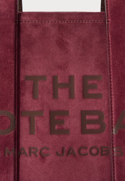 Burgundi sü адвэ сумка rész sötétbarna betűkkel "A TOTESZUMKA" és "MARC JACOBS" hímezve az elülső panelen.
