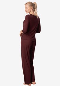 Bordowy zestaw odzieży domowej składający się z bluzki z długim rękawem z koronkowym dekoltem oraz dopasowanych luźnych spodni, wykonany z miękkiego, gładkiego materiału.