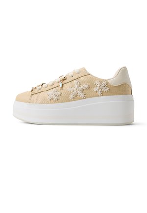 Zapatilla tipo plataforma beige con textura tejida, adornada con diseños florales de perlas y cuentas, cordones blancos y una suela blanca gruesa.