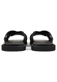Sandali neri con suola piatta, caratterizzati da cinturini incrociati in materiale liscio. Design semplice senza hardware o motivi visibili.