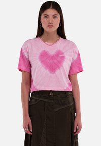 Roze tie-dye crop t-shirt met een hartpatroon in het midden en de tekst "TOMORROW" in het wit. Korte mouwen en een ontspannen pasvorm.