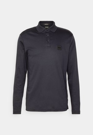 Polo de manga larga en tejido azul marino oscuro. Presenta un cuello clásico, una tapeta de tres botones y un pequeño parche de marca en el pecho.