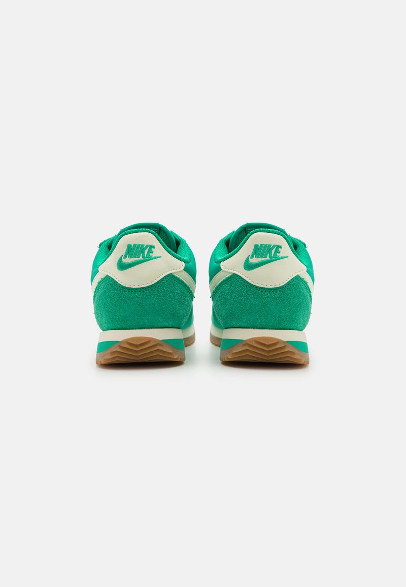 Zapatillas Nike verdes con materiales de ante y textil, que presentan un talón y logotipo beige, suela de goma y detalles texturizados.