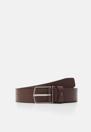 Ceinture en cuir marron foncé avec texture crocodile, boucle métallique rectangulaire argentée et petit logo "CK" sur la boucle de la ceinture.