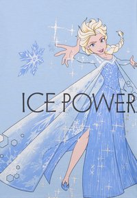 Jasnoniebieska koszulka z grafiką przedstawiającą postać z blond włosami w lśniącej, niebieskiej sukience, ozdobioną płatkami śniegu i iskierkami.