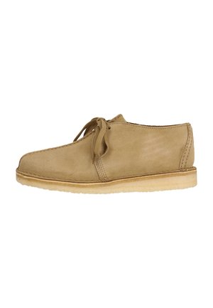 Chaussures en daim beige avec un bout rond, des lacets à nouer et une semelle en crêpe beige. Présentent des coutures le long des bords.