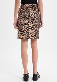 Leopardenmuster-Rock in Tan und Schwarz, aus Denim, mit hinteren Taschen und taillierter Passform. Der Saum endet über dem Knie.