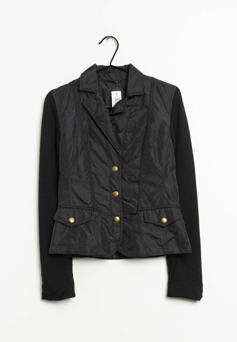 Veste blazer noire pour femme avec devant matelassé, boutons dorés, poches à rabat et manches longues noires unies, suspendue sur un cintre sur fond blanc.
