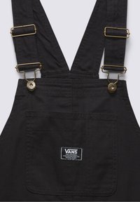 Black Vans overalls with adjustable brass buckles and a front pocket featuring a Vans logo patch.