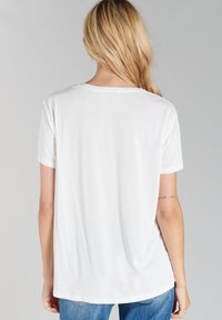 Witte T-shirt met korte mouwen en een ronde hals, zacht van textuur en met een relaxte pasvorm, contrasterende stiksels aan de onderkant. Achteraanzicht weergegeven.