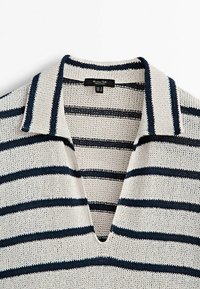 Polo con lavorazione a maglia grigia chiara, con righe orizzontali blu navy e colletto a V profondo, che mostra l'etichetta del marchio all'interno del colletto.