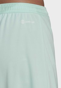 Licht mintgroene sportshorts met een elastische tailleband. Kenmerken "AEROREADY" in het wit gedrukt. Glad stoftextuur, eenvoudig ontwerp.