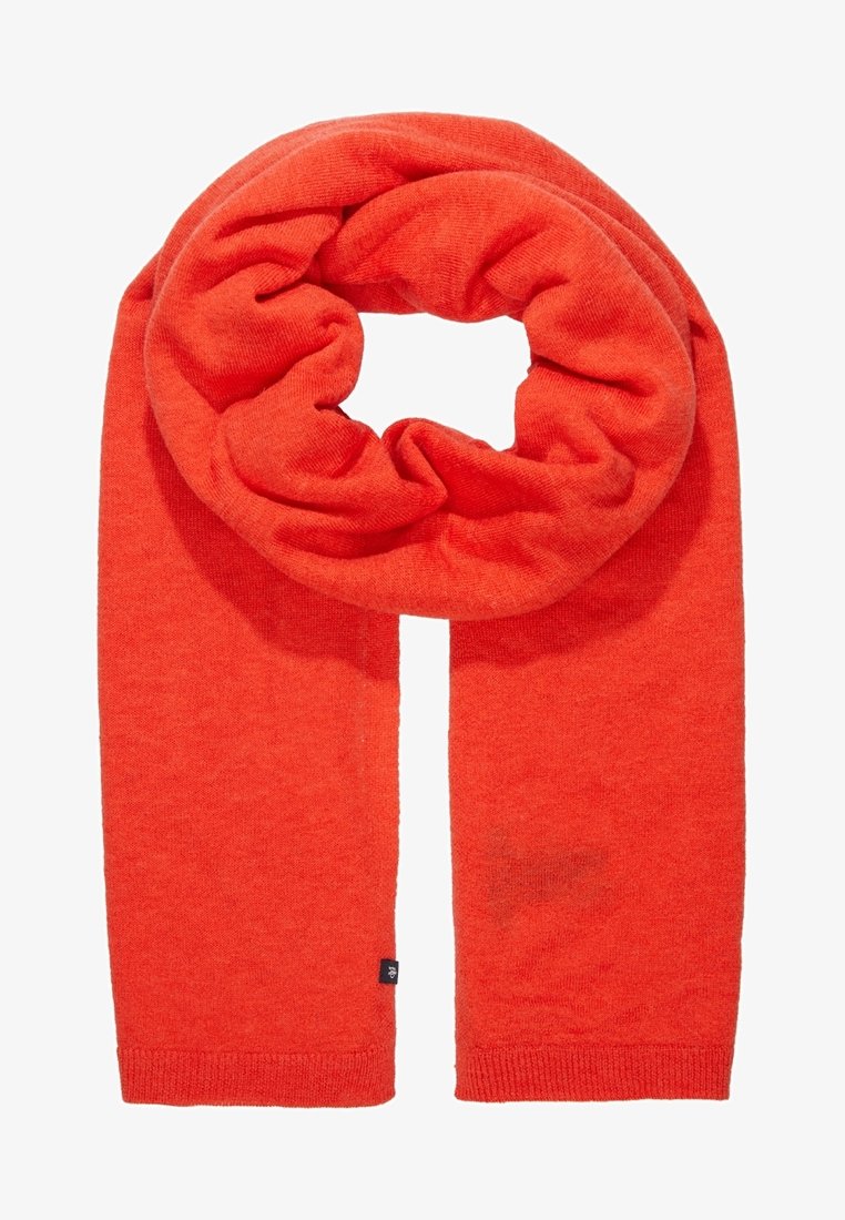 Écharpe tricotée orange vif, soigneusement pliée avec des bords côtelés visibles et une petite étiquette en tissu noir près d'une extrémité.