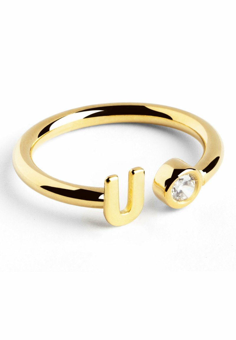 Anello dorato con design a forma di 'U' e un accento di cristallo su un lato, con una finitura liscia e lucida.