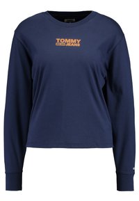 Námořnická modrá košile s dlouhým rukávem vyrobená z měkké tkaniny, se středovým oranžovým logem "TOMMY JEANS" na hrudi a žebrovanými manžetami.