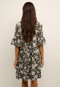 Blumenkleid aus olivgrünem Stoff, mit weißen Blumenmustern, kurzen Rüschelärmeln und einem lockeren, knielangen Schnitt.