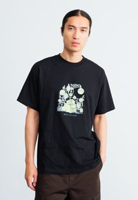 Sort bomulds T-shirt med et cartoon grafisk design i lys grøn, teksten "BEST IN CLASS" nederst, afslappet pasform, korte ærmer.