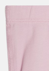 Helle rosa Stoff mit einer glatten Textur, der Nahtdetails entlang der Kante zeigt und ein durchgängiges Rippmuster aufweist.