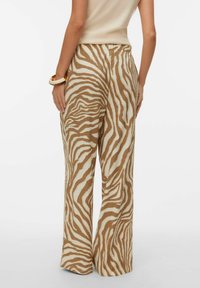 Pantalon à jambes larges en tissu texturé, présentant un motif zébré marron et crème, avec une taille haute et de légers plis.