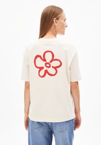 Off-white katoenen t-shirt met een grote rode bloemenprint op de achterkant. Korte mouwen, relaxte pasvorm en ronde hals.