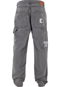 Pantalones cargo grises fabricados con un tejido resistente. Cuentan con dos bolsillos traseros y varios detalles de costura. Incluyen un logo en el bolsillo lateral.