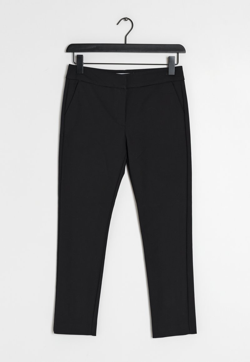 Pantalon noir slim-fit suspendu sur un cintre en plastique noir sur fond blanc.