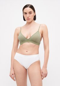 Bralette triangular em algodão verde-azeitona com alças ajustáveis, combinado com cuecas de algodão brancas de cintura alta. Textura suave, design minimalista.